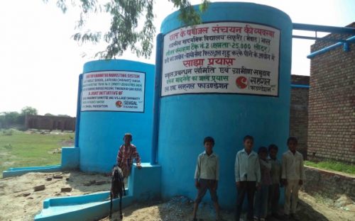 Children standing before a water tank in the village of Lafuri in Haryana.